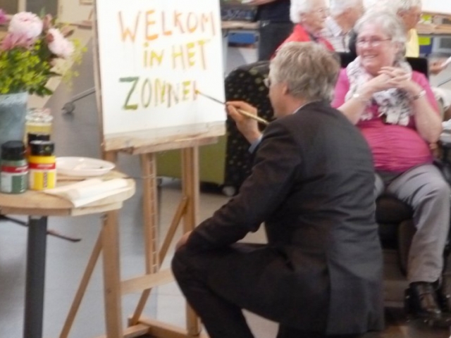 Dhr. swart maakt een schilderij in samenwerking met een van de bewoners.