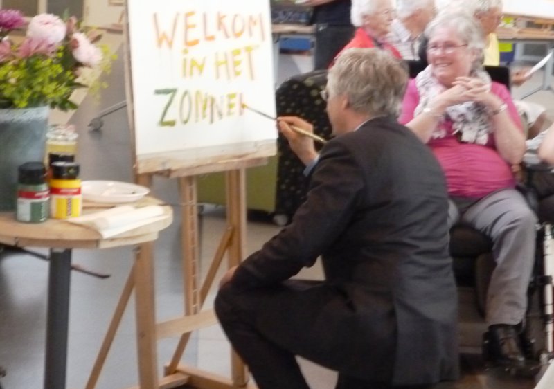 Dhr. swart maakt een schilderij in samenwerking met een van de bewoners.